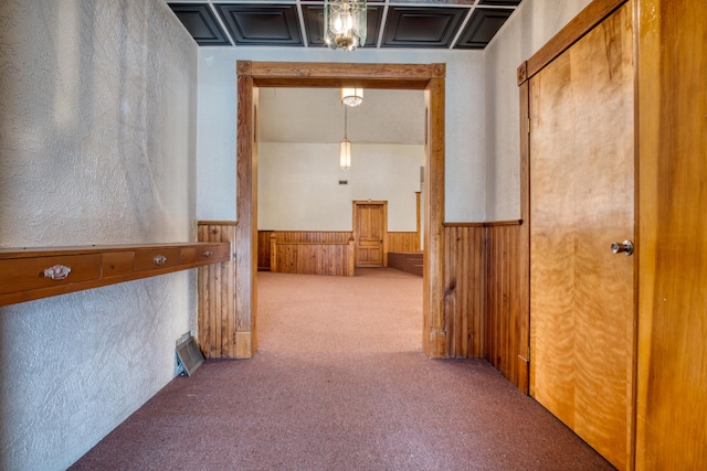 hallway featuring carpet floors, a wainscoted wall, and wood walls