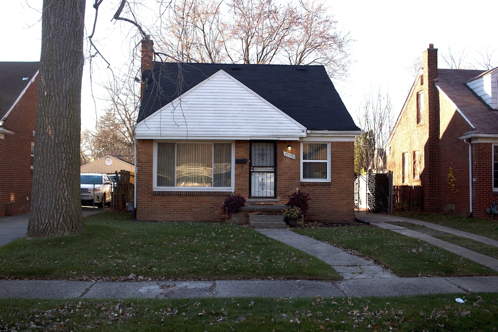 bungalow-style house featuring a front lawn and brick siding