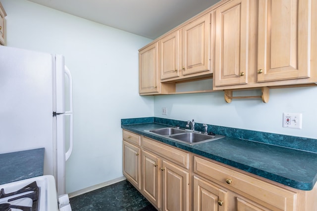 kitchen featuring freestanding refrigerator, light brown cabinetry, a sink, stove, and dark countertops