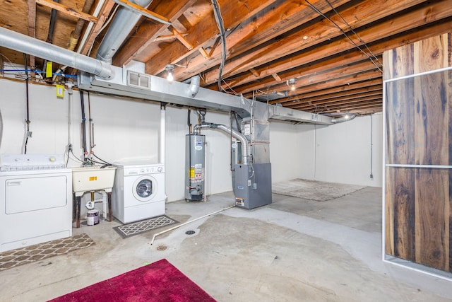 unfinished below grade area featuring visible vents, water heater, heating unit, independent washer and dryer, and a sink