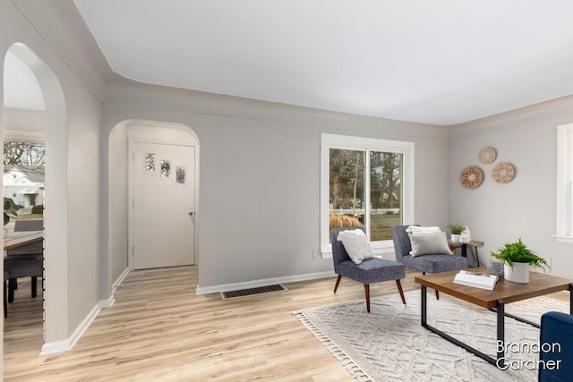 entrance foyer with arched walkways, baseboards, visible vents, and light wood finished floors