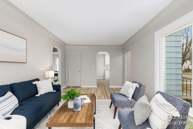 living room featuring arched walkways, wood finished floors, and baseboards