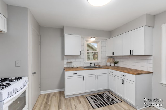 kitchen with light wood-style floors, butcher block counters, a sink, and tasteful backsplash