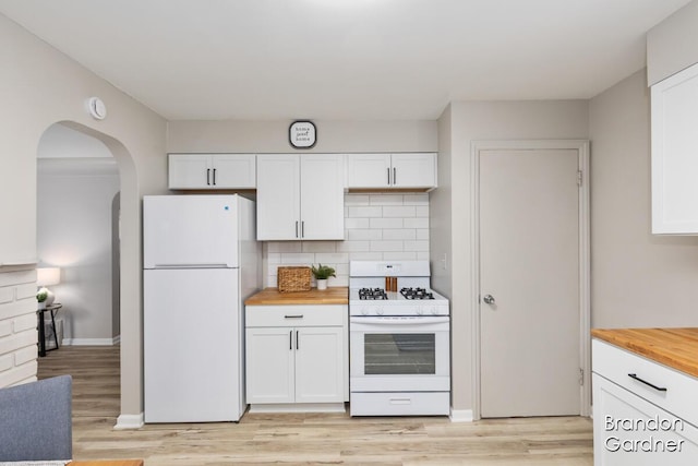 kitchen with white appliances, light wood finished floors, white cabinets, decorative backsplash, and wooden counters