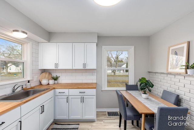 kitchen featuring wooden counters, tasteful backsplash, plenty of natural light, and a sink