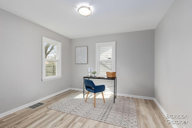 office area with light wood finished floors, visible vents, and baseboards