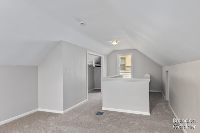 additional living space with carpet floors, lofted ceiling, visible vents, and baseboards