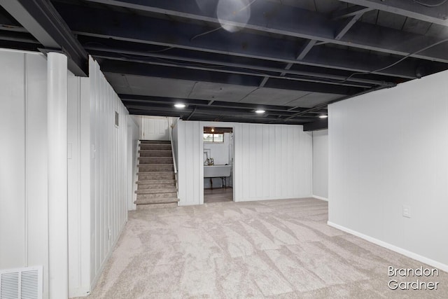 basement featuring stairs, carpet floors, a sink, and visible vents