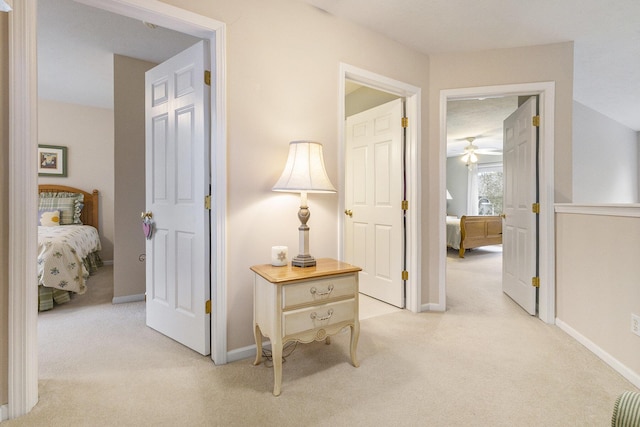 hall featuring baseboards and light colored carpet