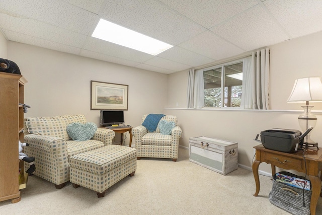 living area with carpet floors and a paneled ceiling