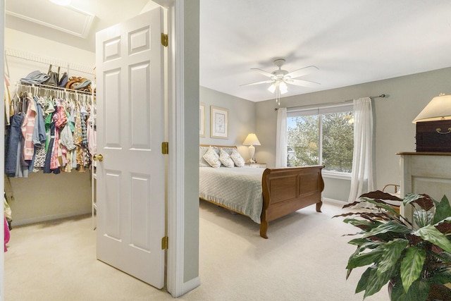 bedroom with light carpet, attic access, baseboards, a ceiling fan, and a closet