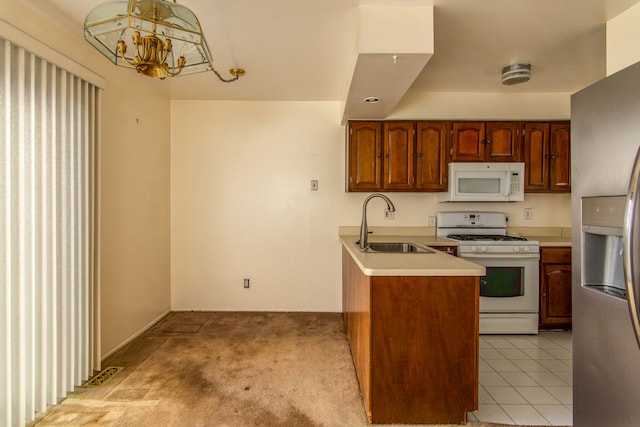 kitchen featuring a notable chandelier, light tile patterned floors, light carpet, a sink, and white appliances