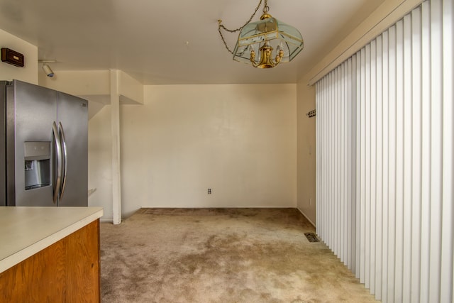 kitchen with light colored carpet, stainless steel fridge, visible vents, and an inviting chandelier