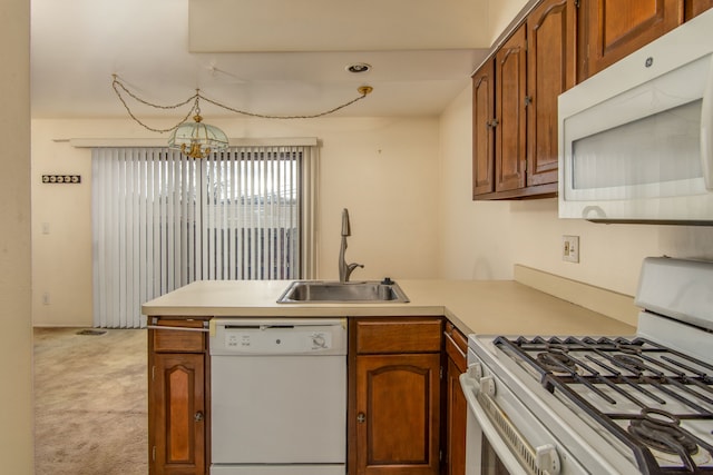 kitchen featuring light carpet, white appliances, brown cabinets, a peninsula, and a sink