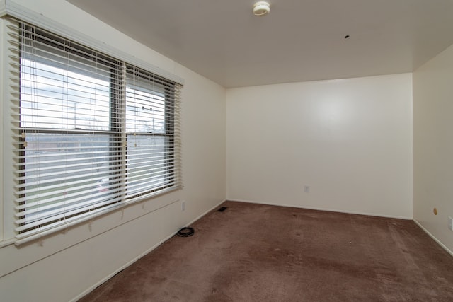 unfurnished room featuring carpet floors and baseboards