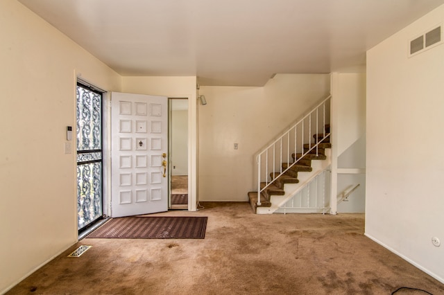 entrance foyer featuring stairs, carpet flooring, and visible vents