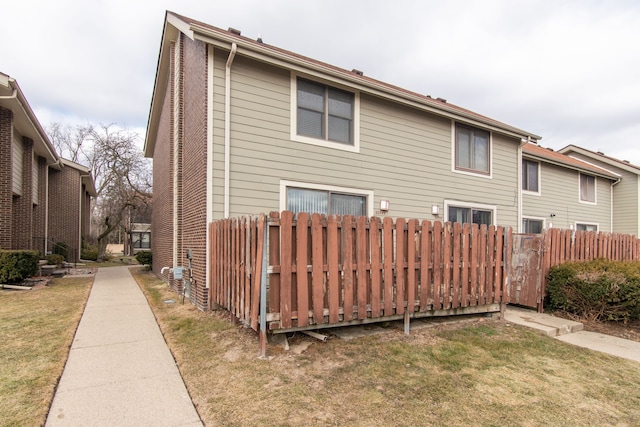 back of property featuring fence and a lawn