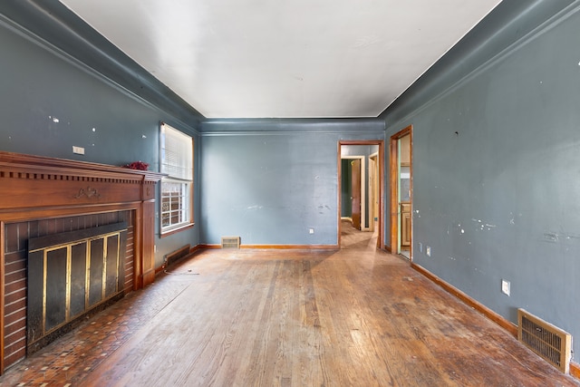 unfurnished living room featuring baseboards, visible vents, a fireplace, and hardwood / wood-style floors