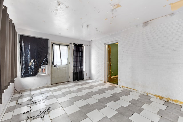 empty room featuring light floors and brick wall