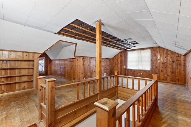 additional living space with vaulted ceiling, hardwood / wood-style floors, and wooden walls