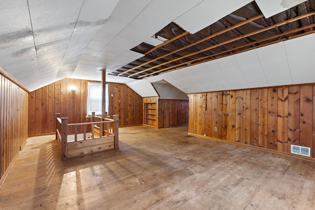 bonus room featuring lofted ceiling, hardwood / wood-style flooring, wooden walls, and visible vents