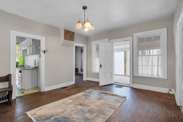 foyer entrance featuring a notable chandelier, visible vents, baseboards, and dark wood-type flooring