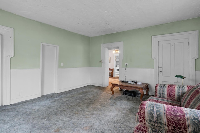 living area with carpet floors, a wainscoted wall, and a textured ceiling