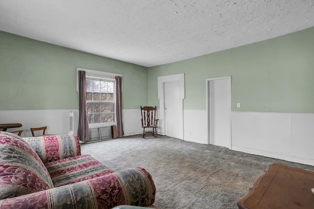 living room with carpet floors, a wainscoted wall, and a textured ceiling