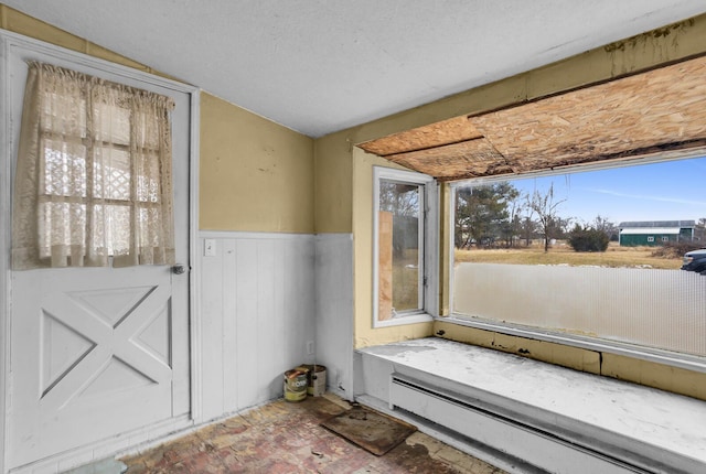 doorway to outside with a baseboard radiator and a wainscoted wall