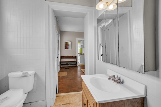 bathroom featuring toilet, tile patterned floors, tile walls, and vanity