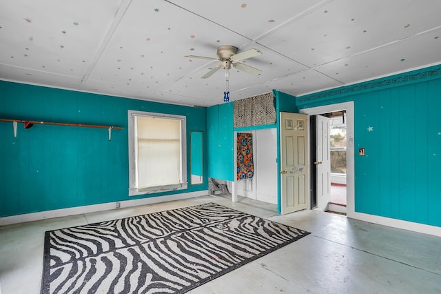 empty room featuring ceiling fan, finished concrete flooring, and baseboards