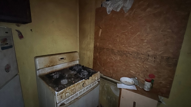 kitchen with white range with gas stovetop and fridge