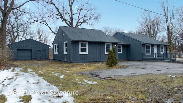 view of front of property with an outbuilding, a detached garage, driveway, and a shingled roof