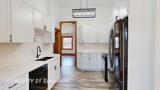 kitchen featuring black appliances, a sink, light wood finished floors, and white cabinetry