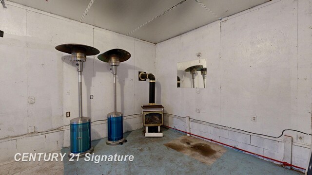 misc room with unfinished concrete floors and a wood stove