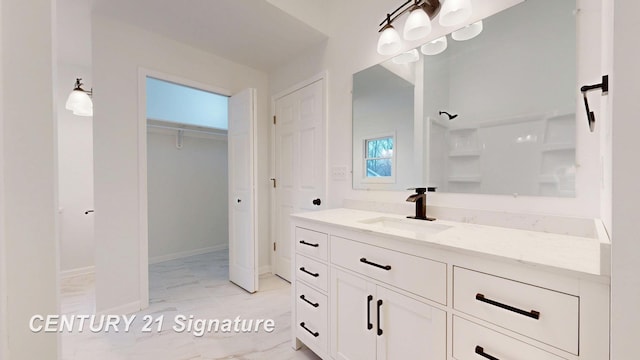 bathroom with vanity, marble finish flooring, a spacious closet, a shower, and baseboards