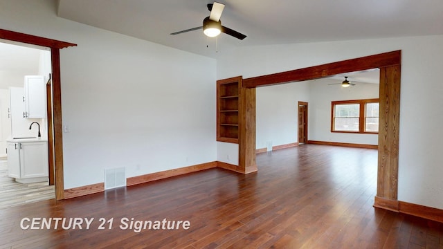 spare room featuring a ceiling fan, a sink, vaulted ceiling, wood finished floors, and baseboards
