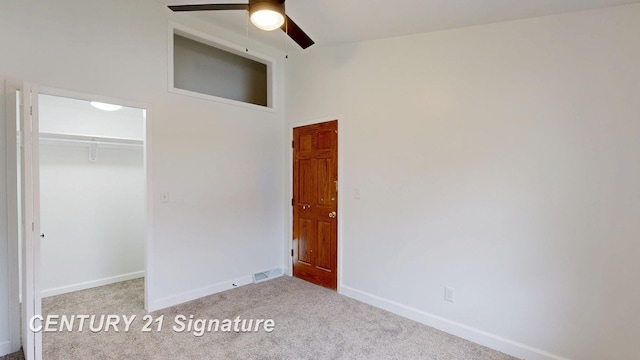 unfurnished bedroom featuring carpet, baseboards, a closet, and a ceiling fan