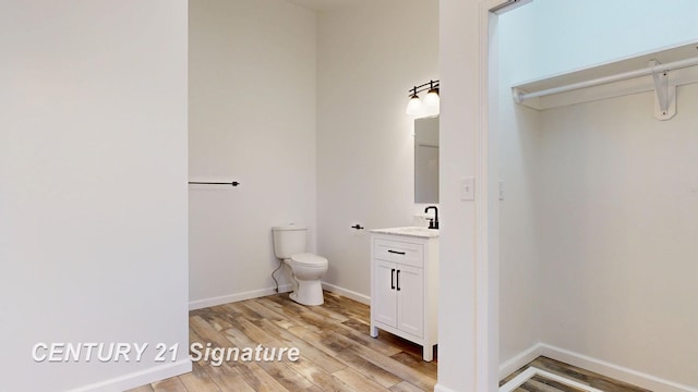 bathroom featuring toilet, wood finished floors, vanity, and baseboards