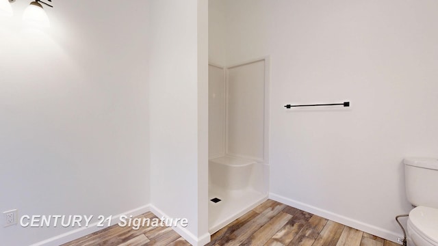 bathroom with wood finished floors, toilet, baseboards, and a shower