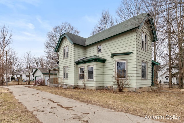 view of front of home featuring a garage, fence, and an outbuilding