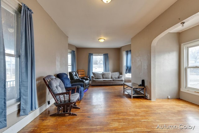 living area with arched walkways and wood finished floors