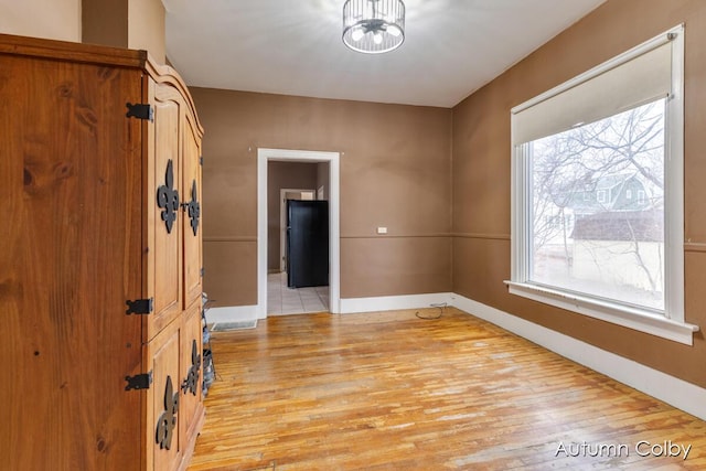 unfurnished room featuring baseboards and light wood finished floors