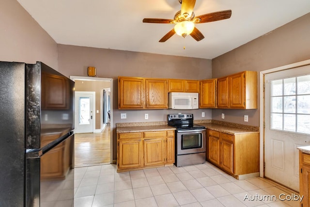 kitchen with white microwave, a ceiling fan, freestanding refrigerator, brown cabinets, and stainless steel electric range oven