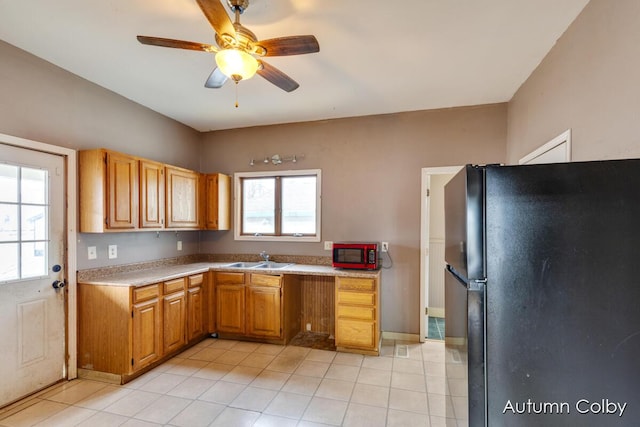 kitchen featuring light tile patterned floors, a ceiling fan, freestanding refrigerator, light countertops, and a sink