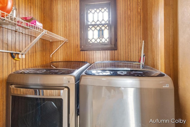 laundry room featuring laundry area, wood walls, and washer and clothes dryer