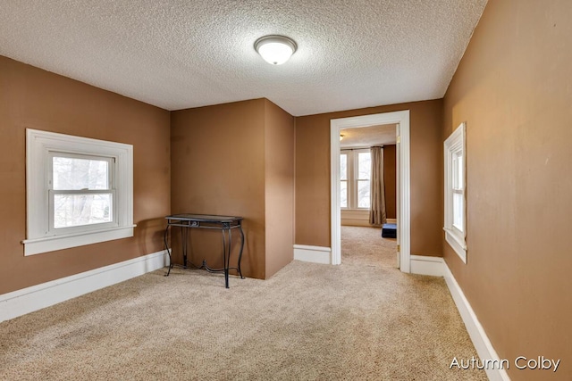 spare room featuring carpet flooring, a textured ceiling, and baseboards