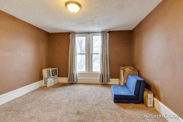 unfurnished room with carpet floors, baseboards, and a textured ceiling