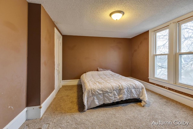 bedroom with carpet, a textured ceiling, and baseboards