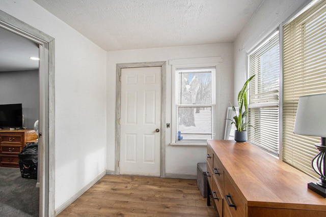 home office featuring baseboards, a textured ceiling, and light wood-style floors